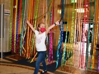 Radosna dziewczynka przechodzi przez kolorowe wstążki powieszone w drzwiach holu