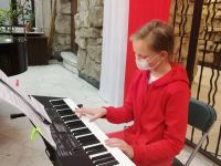 dziewczyna grająca na keyboardzie na tle biało-czerwonej flagi
