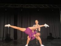dwie uczestniczki w akrobatycznej pozie na scenie.