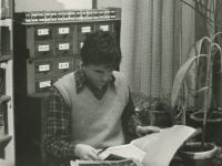 chłopiec w bibliotece czytający gazetę