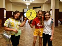 Trzy dziewczęta prezentują symbol Gry „Pałac Talentów”