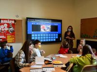 Instruktorka prezentuje dzieciom grę interaktywną w języku hiszpańskim