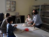 Instruktorka ceramiki wyjaśnia dzieciom i mamie jak lepić z gliny