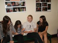 4 dziewcząt siedzacych na ławeczce i rozwiązujacych zadania