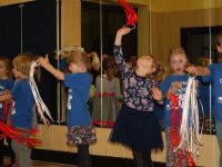 dzieci  śpiewają i ruszają w rytm muzyki biało czerwonymi wstążkami